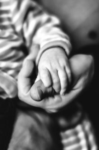 black-and-white-image-of-baby-boy-holding-fathers-hand
